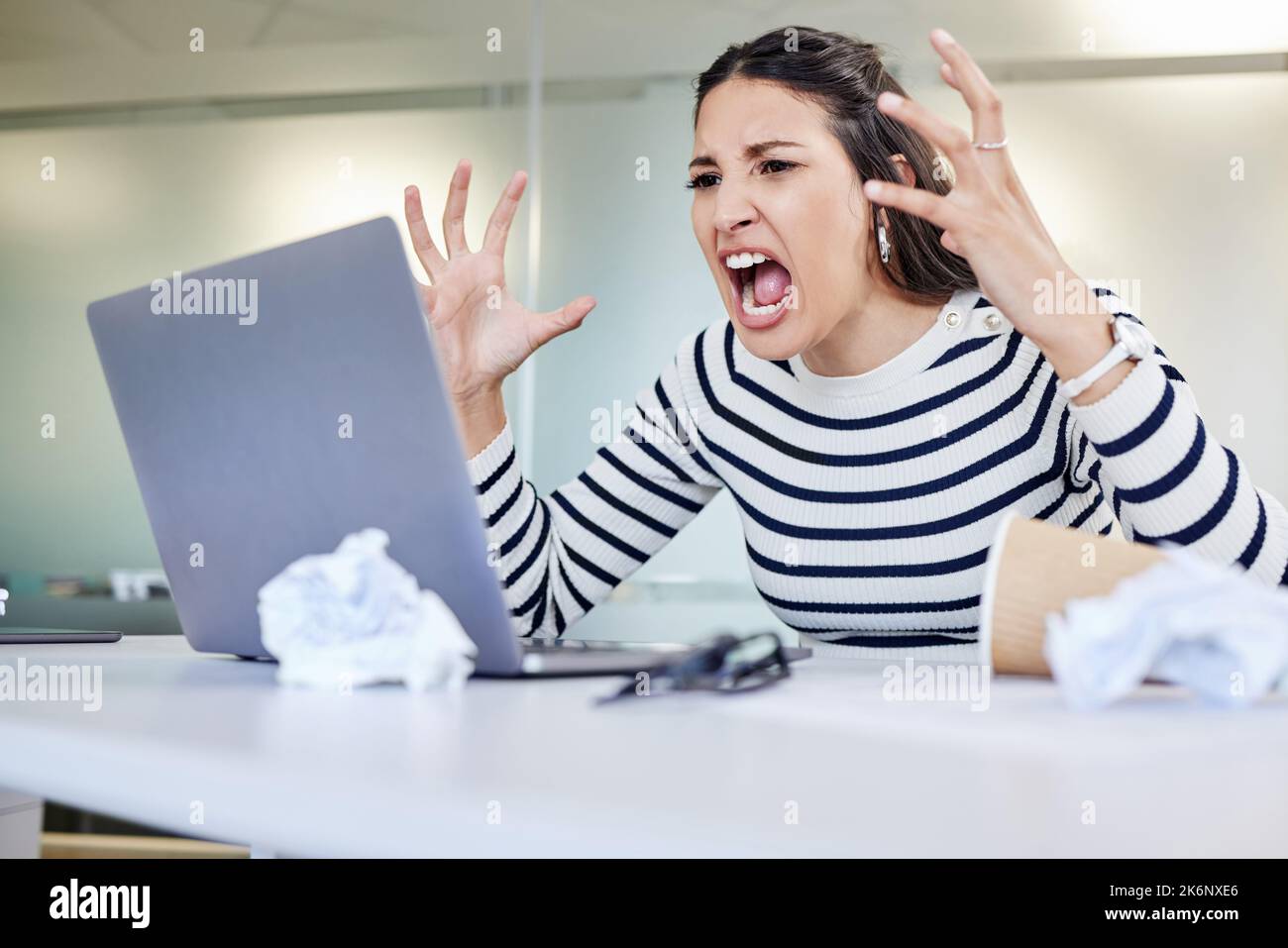 Was alles so langsam macht. Eine junge Geschäftsfrau, die wütend aussieht, während sie im Büro einen Laptop benutzt. Stockfoto