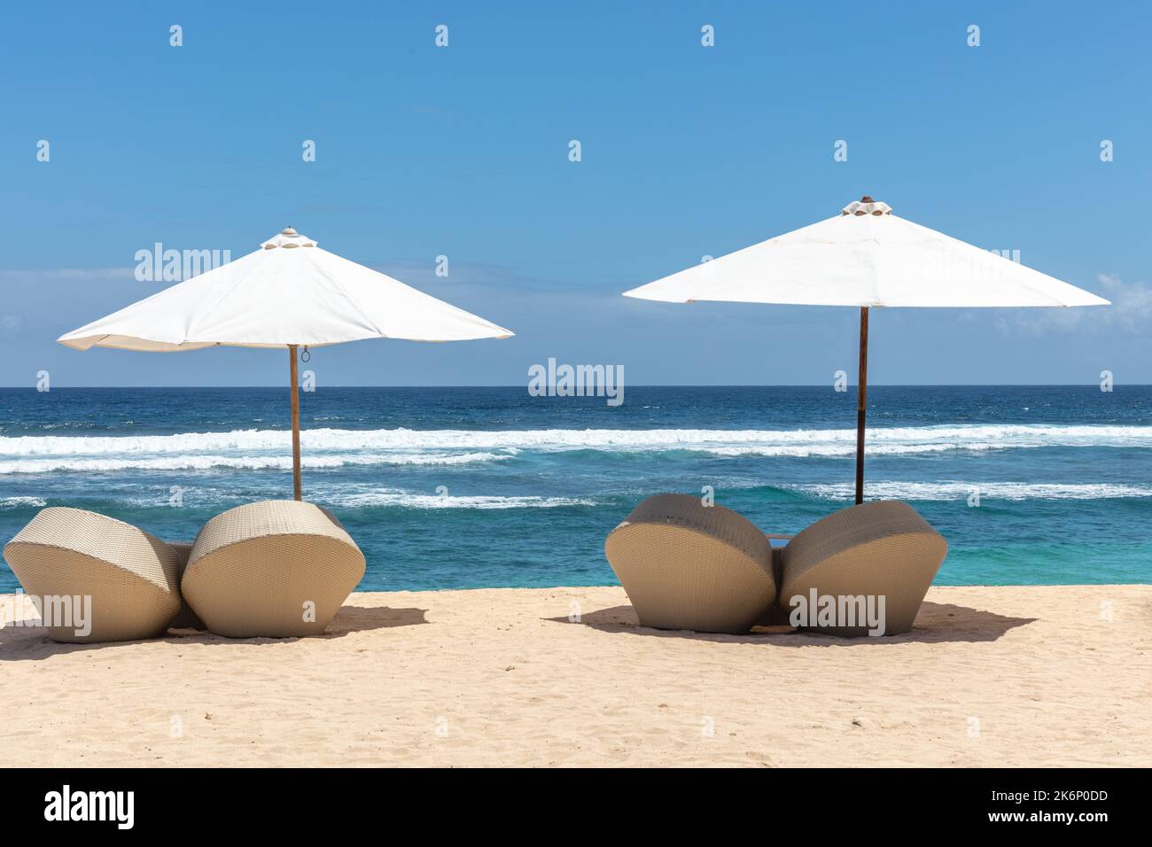 Beliebte Melasti Beach (Pantai Melasti), Bukit, Bali, Indonesien. Türkisfarbenes Wasser, Meereslandschaft, weiße Sonnenschirme mit Liegestühlen. Stockfoto