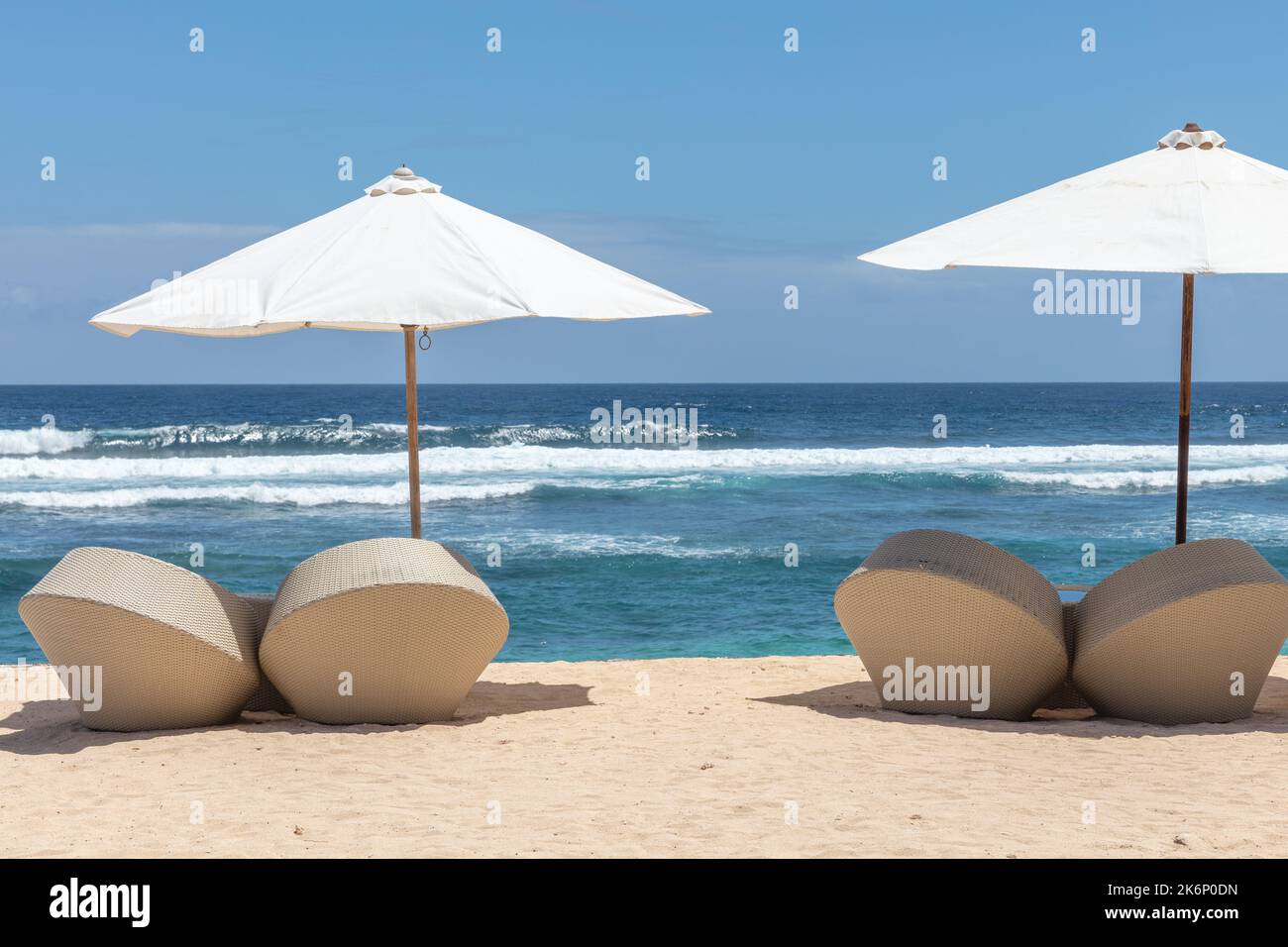 Beliebte Melasti Beach (Pantai Melasti), Bukit, Bali, Indonesien. Türkisfarbenes Wasser, Meereslandschaft, weiße Sonnenschirme mit Liegestühlen. Stockfoto