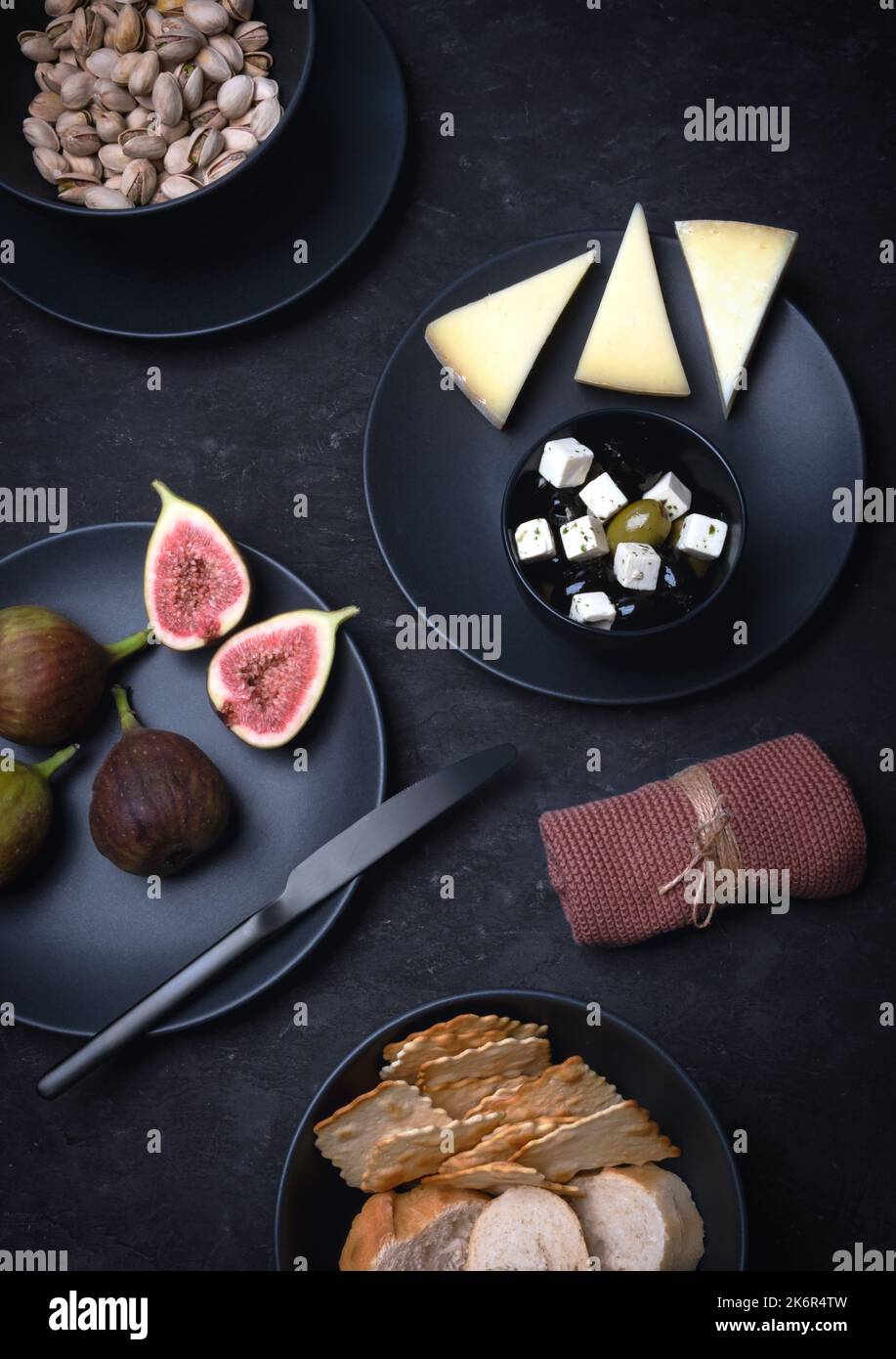 Käseplatte mit Käse und Nüssen, mediterrane Speisen auf schwarzem Hintergrund Stockfoto