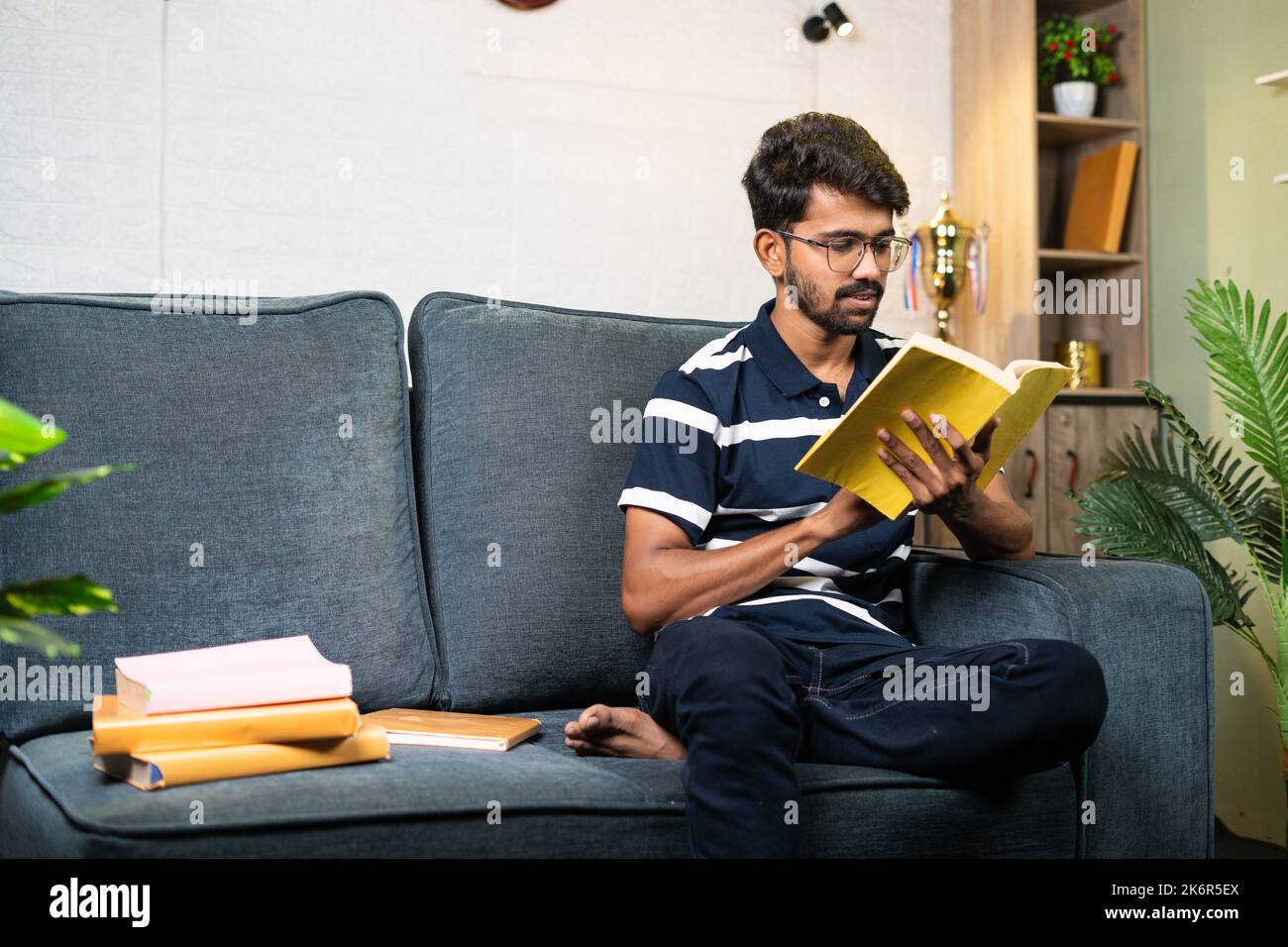 Ernsthafte junge indische Student Buch während der Freizeit zu Hause zu lesen - Konzept der Bildung, Hobbys und harte Arbeiter. Stockfoto
