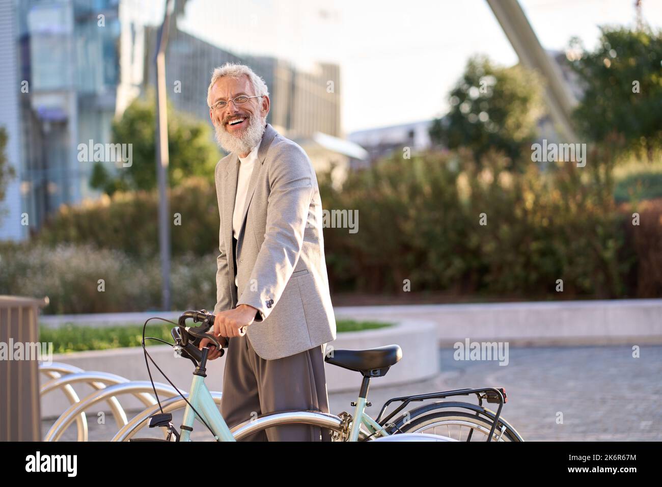 Glücklich, aktiv, lächelnd, alter grauhaariger Mann, der im Stadtpark ein Fahrrad mietet. Stockfoto