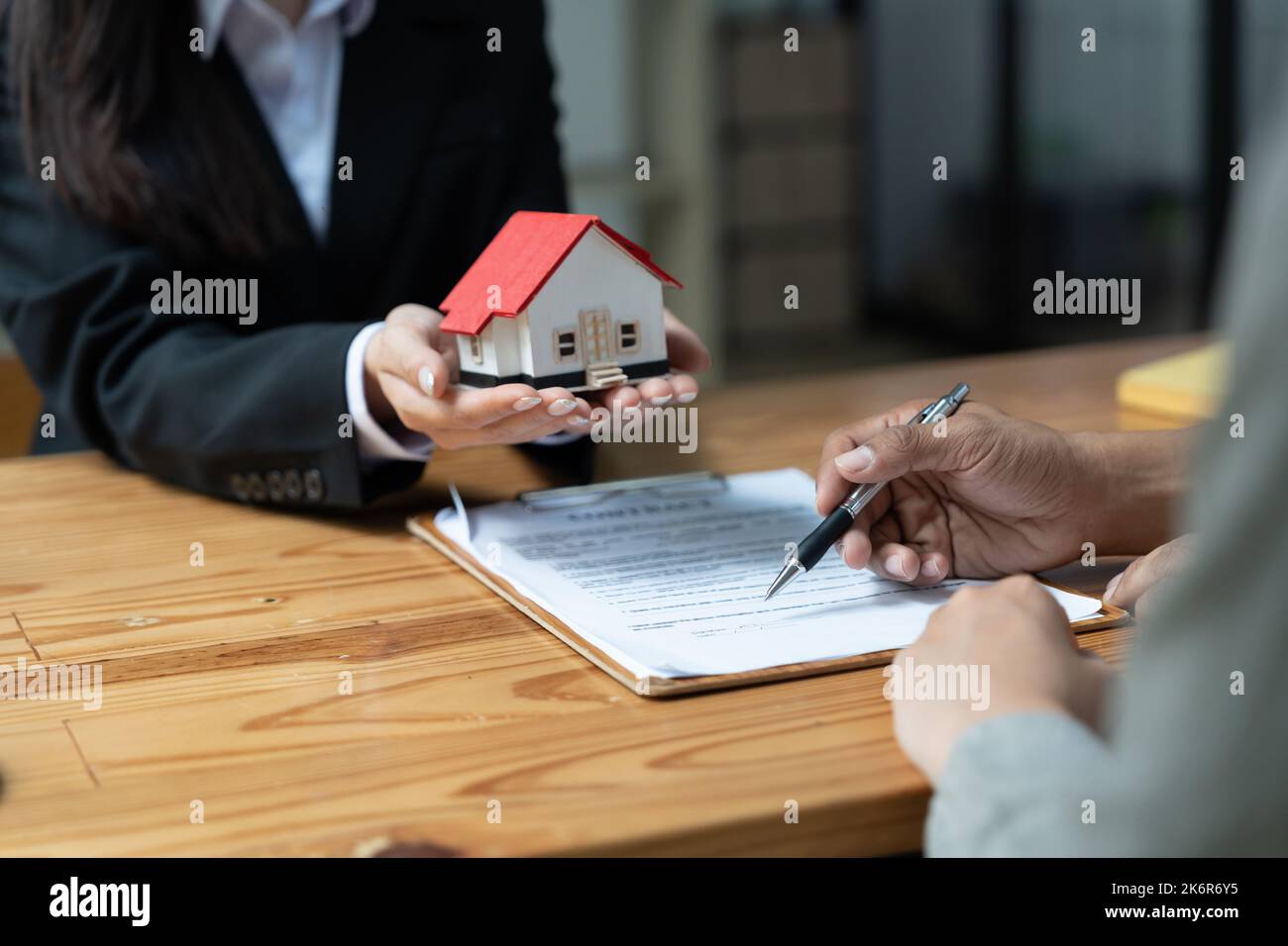 Immobilienmakler mit Kunden, die einen Deal abschließen und einen Vertrag unterzeichnen. Stockfoto