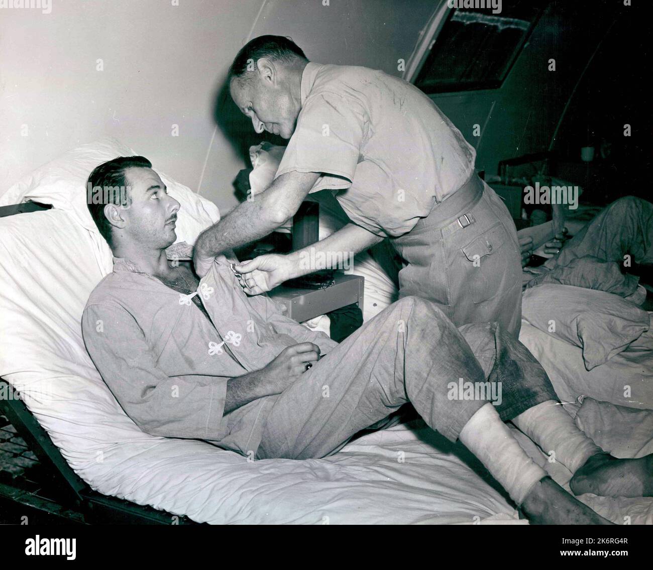 Foto von Admiral Raymond A. Spruance, Kommandant der Fünften Flotte, der Clarence E. McElroy, der ein Überlebender der der Cruiser USS Indianapolis (CA-35) in Guam ist, mit einem purpurnen Herzen anpinnt Stockfoto