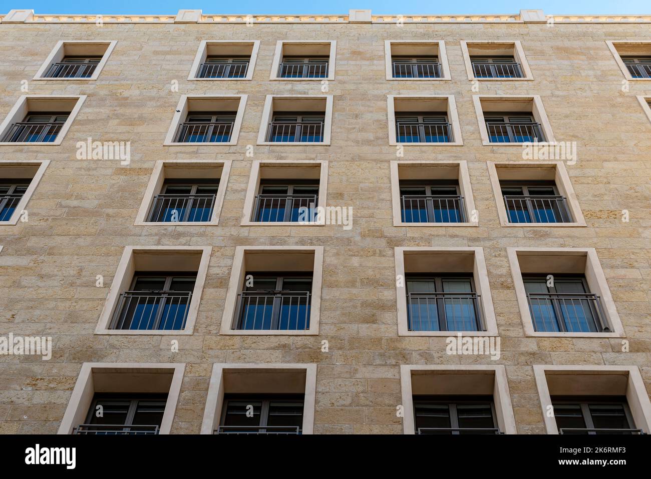 Schwarze lange, dünne rechteckige Fenster im Neubau. Viele Fenster dunkelbraune Farbe auf dem Haus. Steingebäude mit vielen Fenstern Stockfoto