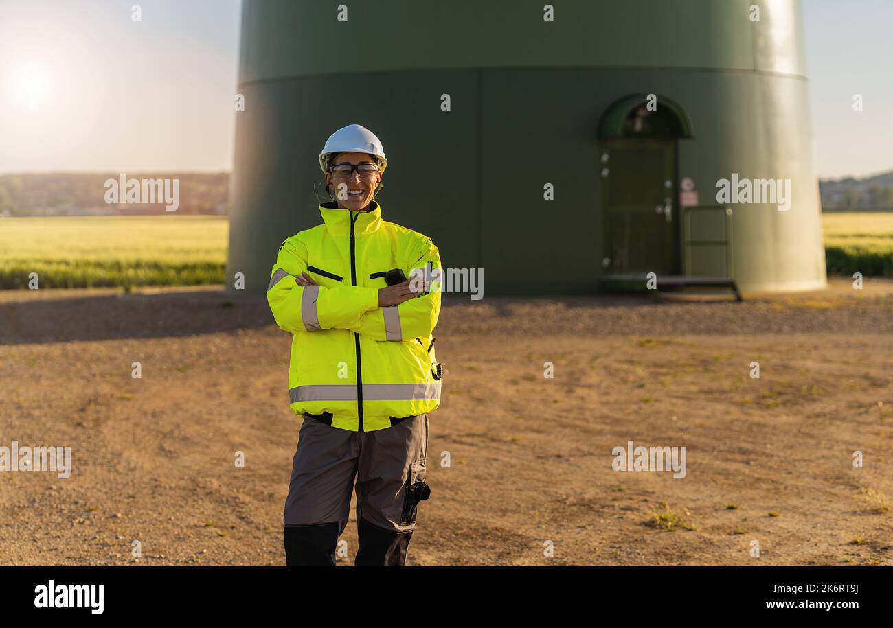 Ingenieurin mit Schutzhülle, die vor einer Windkraftanlage auf einem neuen Energiepark steht. Bild des Konzepts der regenerativen Energie Stockfoto