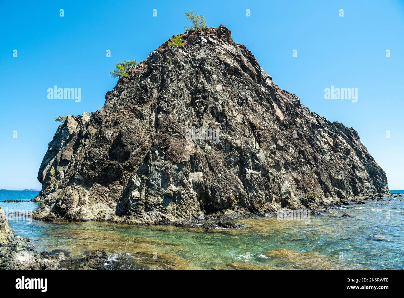 Kleine felsige Insel, die an das Hauptland im Dorf Cirali der Provinz Antalya in der Türkei angrenzt. Stockfoto