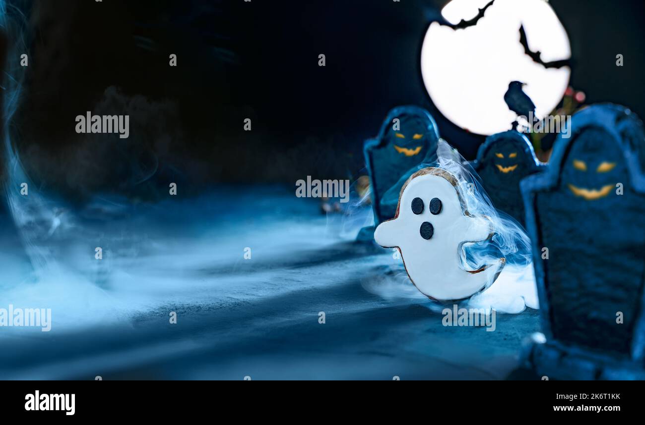 Breites Halloween-Banner mit niedlichem Geist, der nachts auf dem Friedhof zwischen Grabsteinen unter dem blauen Licht des Mondes fliegt. Fledermaus Silhouetten. Friedhof in t Stockfoto