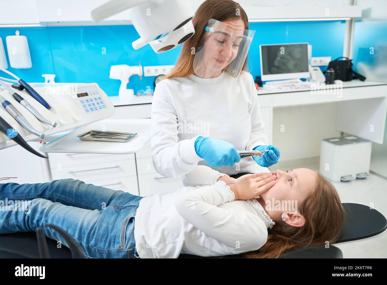 Erfahrene pädiatrische Zahnärztin zerstreut die Angst des Patienten vor der Zahnextraktion Stockfoto