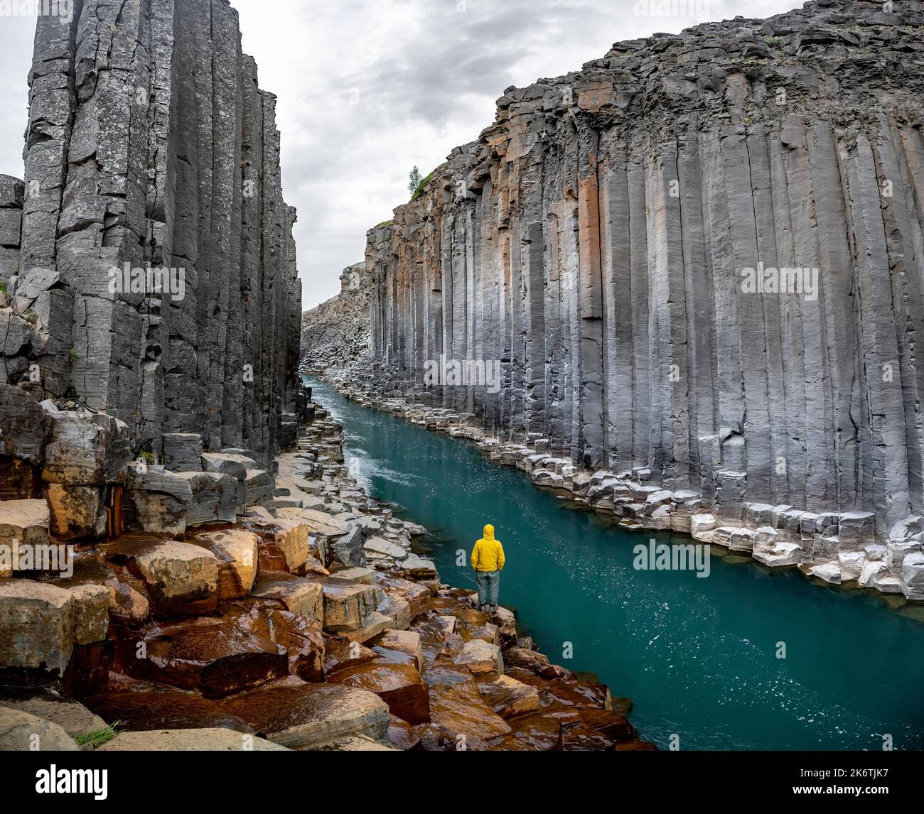 Tourist steht am Fluss im Stuolagil Canyon, türkisblauer Fluss zwischen Basaltsäulen, Egilsstadir, Island Stockfoto