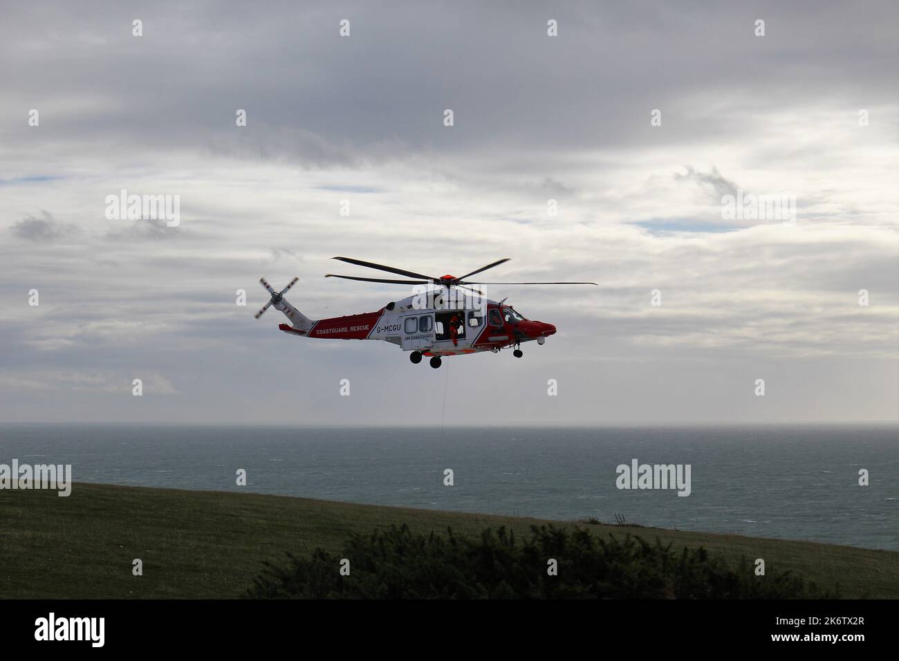 Seven Sisters Cliffs, Großbritannien. 15. Oktober 2022. Ein Hubschrauber schwebt über der Schwesternklippe Haven Brow im Seven Sisters Country Park, während Such- und Rettungskräfte in der Nähe stehen. Dies ist eine weitere Folge von über 100 Zwischenfällen in diesem Jahr, die an den Klippen stattgefunden haben, wo ein neuer Seilzaun installiert werden soll. Kredit: Aldercy Carling/ Alamy Live Nachrichten Stockfoto