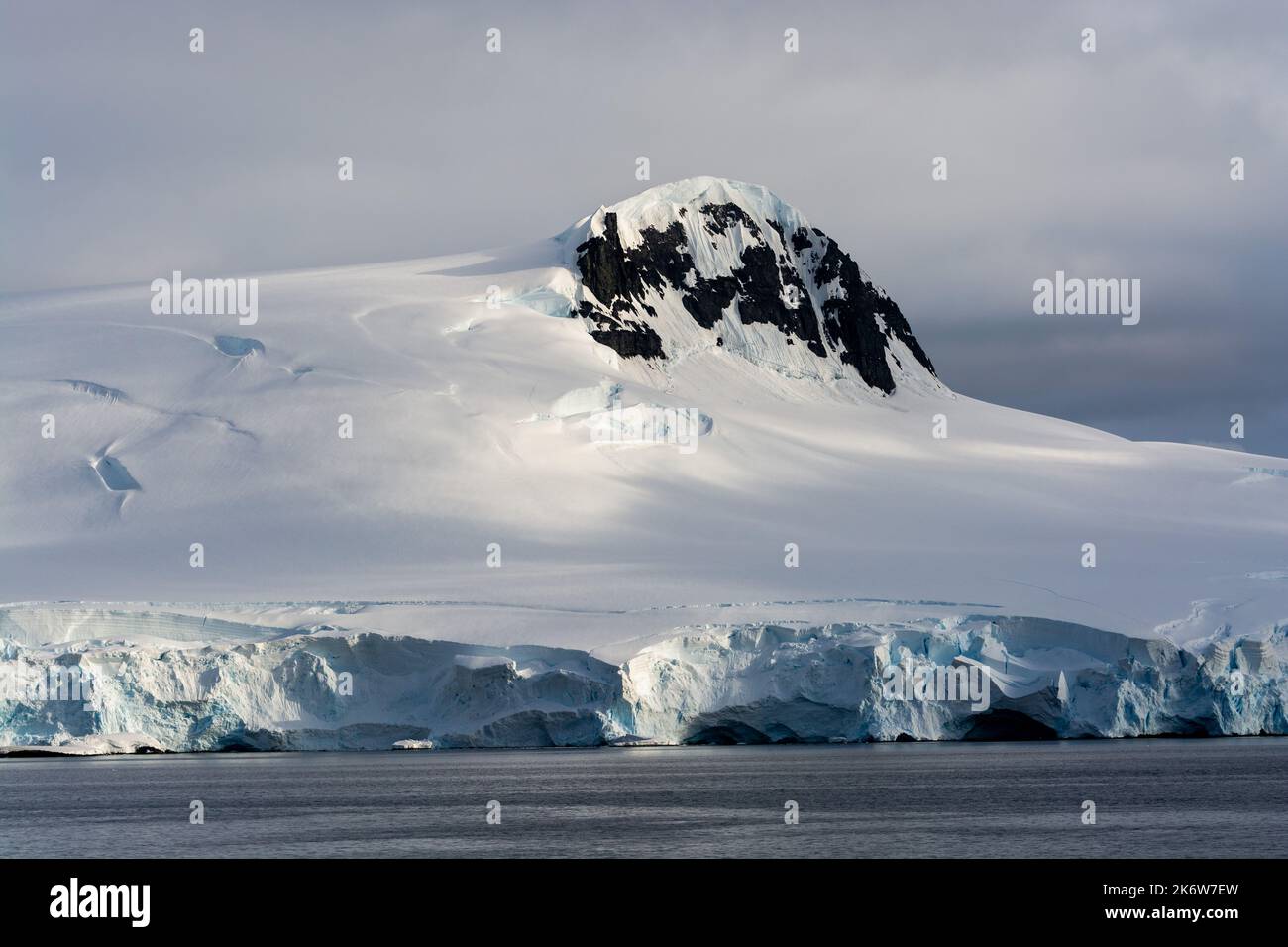 Eis- und schneebedeckte Küste mit felsigen Ausbissen. dallmann Bay. antarktische Halbinsel. Antarktis Stockfoto