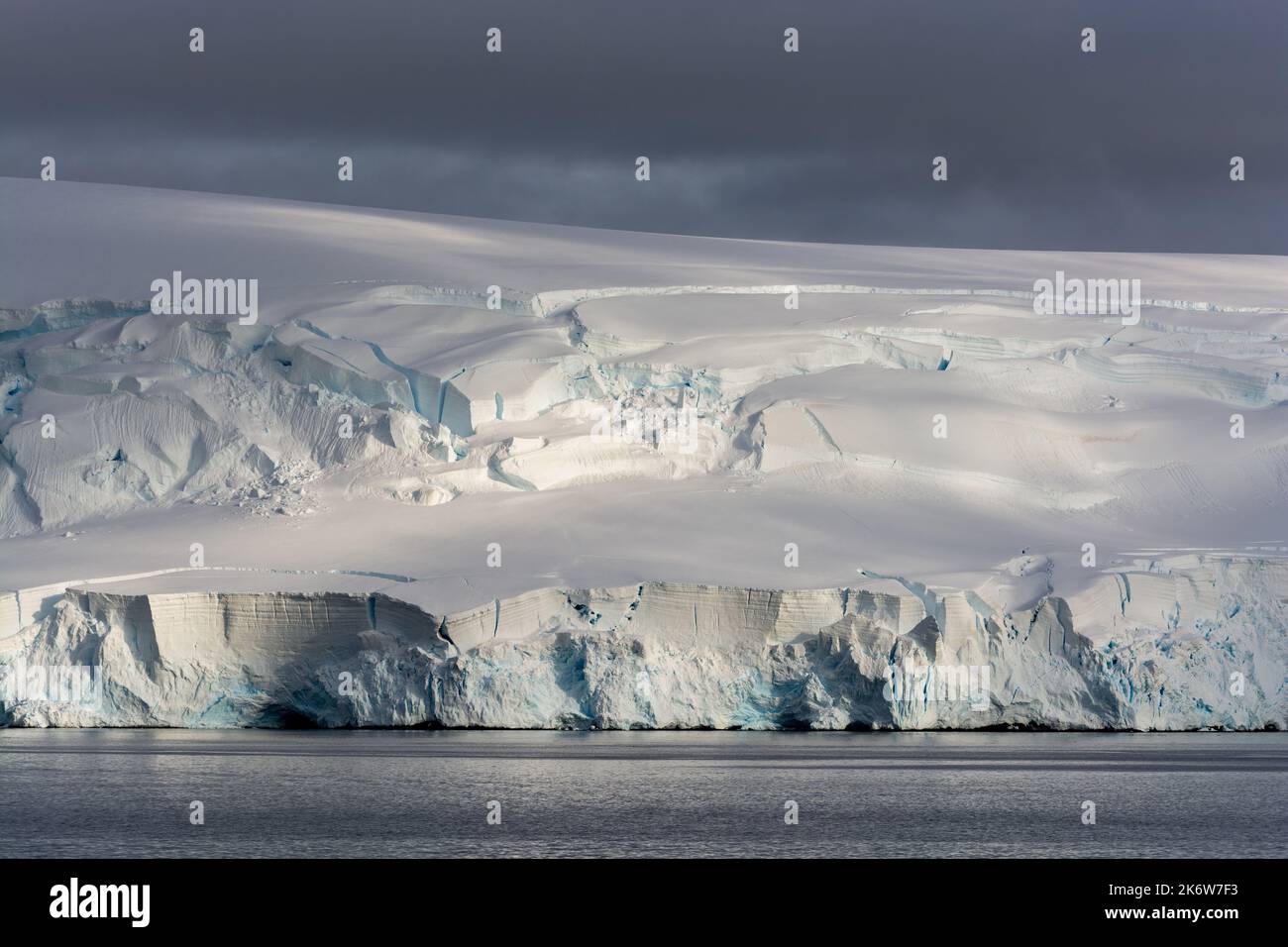 Am frühen Morgen Beleuchtung auf hoch gemusterten Schnee- und Eisklippen an der Küste. dallmann Bay. antarktische Halbinsel. Antarktis Stockfoto