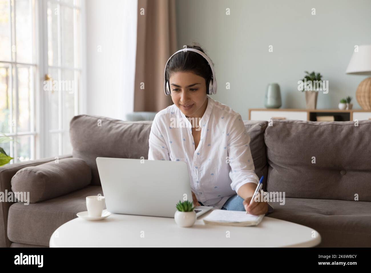 Frau trägt Kopfhörer, macht Sport, E-Learning zu Hause mit einem Laptop Stockfoto