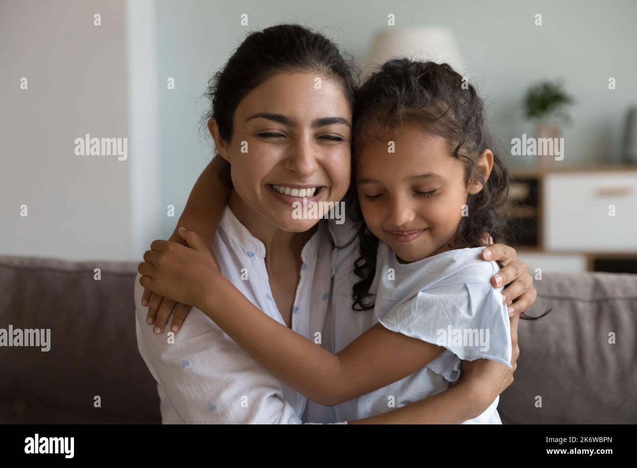 Liebevolle Mutter kuscheln Tochter sitzen auf dem Sofa Genießen Sie zarten Moment Stockfoto