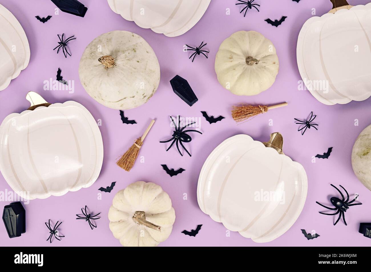 Halloween Party flach lag mit Kürbis geformten Tellern, Kürbissen, Hexenbesen, Spinnen und Särgen auf violettem Hintergrund Stockfoto
