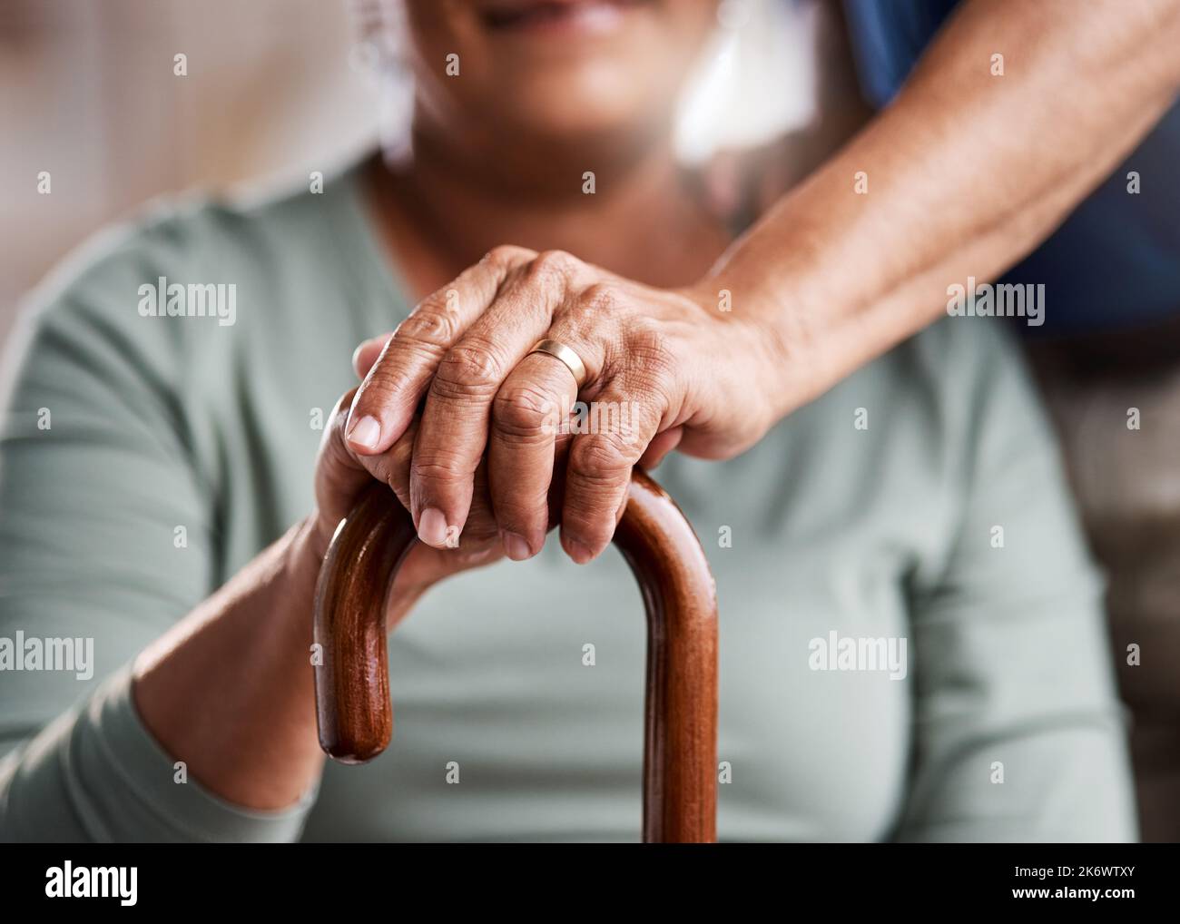 Du wirst nie alleine gehen. Eine nicht erkennbare ältere Frau, die sich zu Hause in ihren Gehstock lehnt. Stockfoto