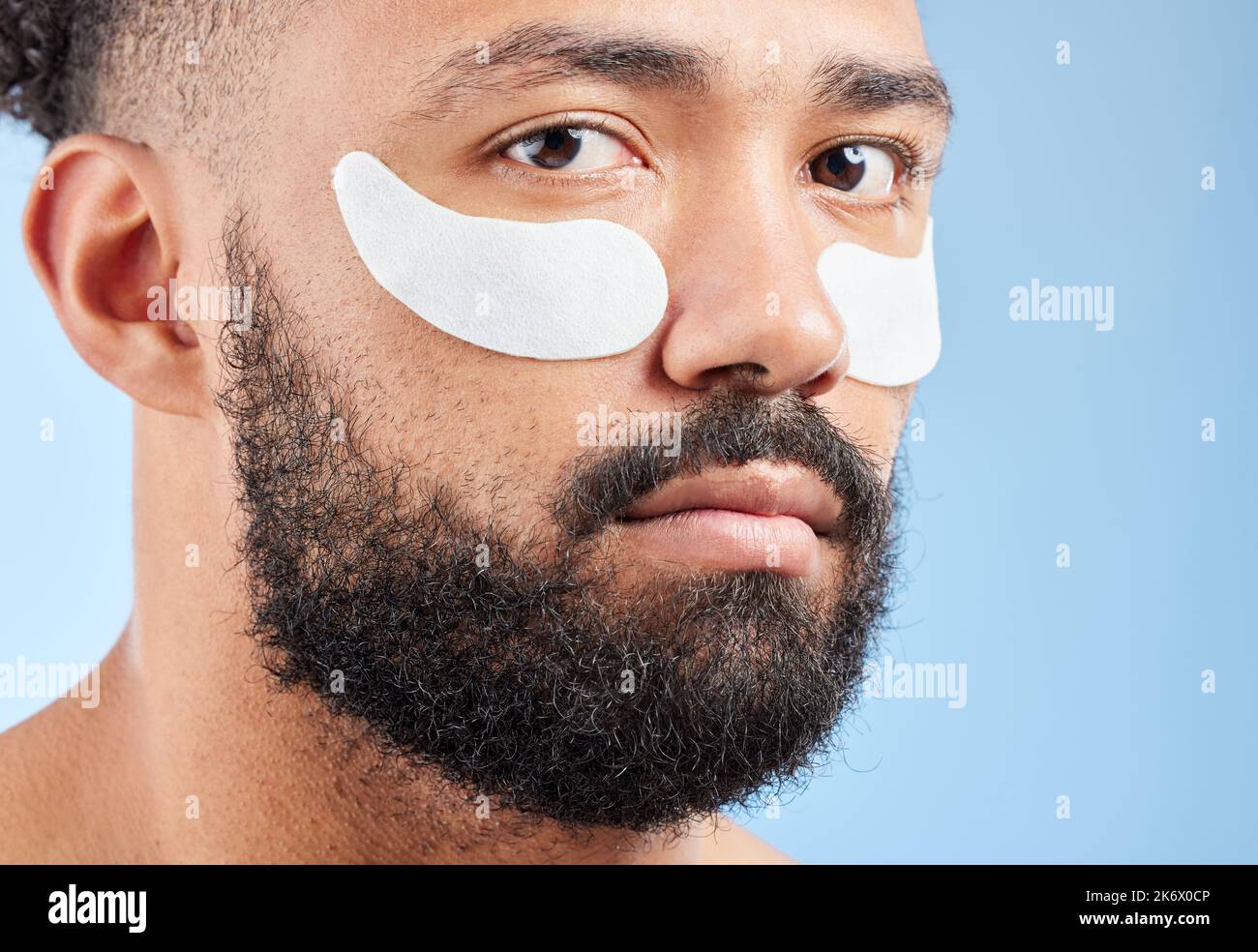 Lassen Sie sich nicht die Falten gewinnen. Studioporträt eines hübschen jungen Mannes, der unter Augenflecken vor blauem Hintergrund getragen wird. Stockfoto