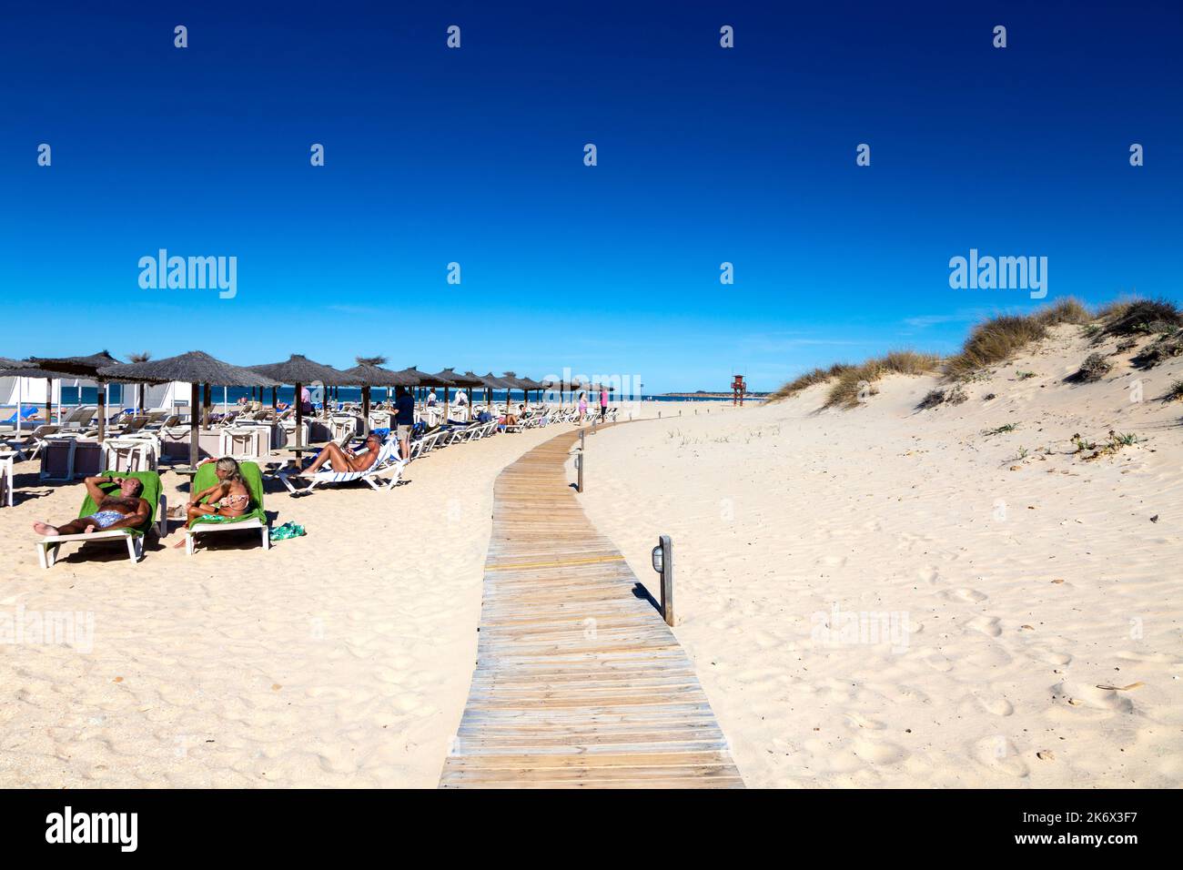 Holzsteg und Strohschirme am Playa de la Barrosa, Cadiz, Spanien Stockfoto