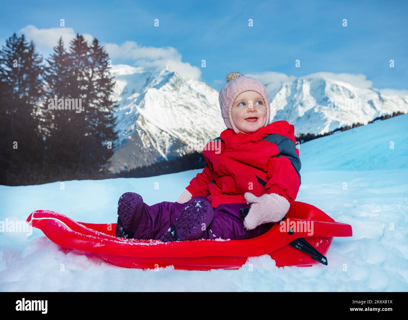 Glückliches kleines Mädchen geht im Schlitten bergab Stockfoto