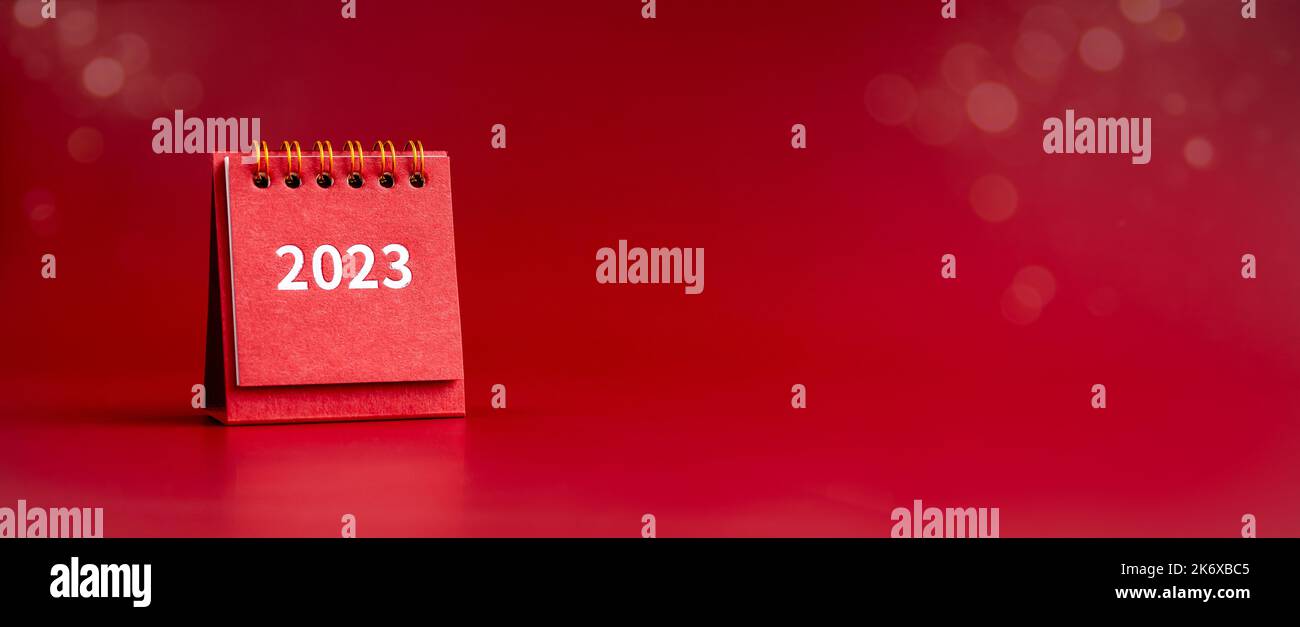 Frohes neues Jahr 2023 Banner. 2023 Zahlen Jahr auf kleinen roten Schreibtisch Kalender Abdeckung isoliert auf rotem Hintergrund mit Kopieplatz, minimalistisch. Startklar Stockfoto