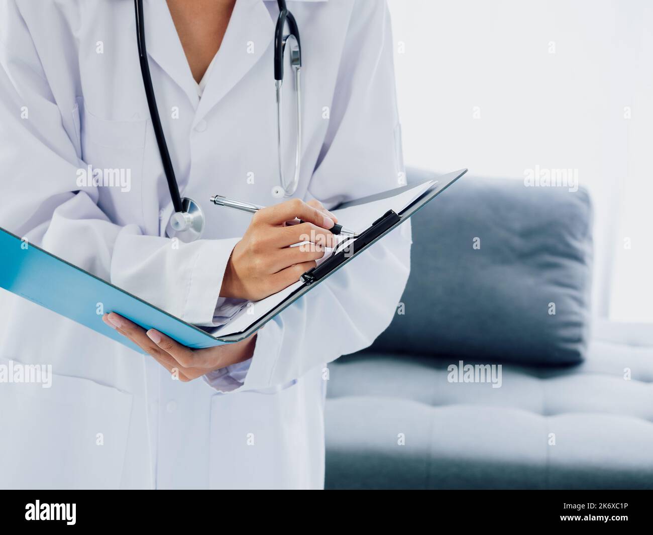 Arzt mit Papierakte. Weibliche Ärzte Hand schreibt medizinische Dokument oder Patienten Untersuchungsnotizen mit Stift auf Zwischenablage. Arzt in weißem Anzug w Stockfoto
