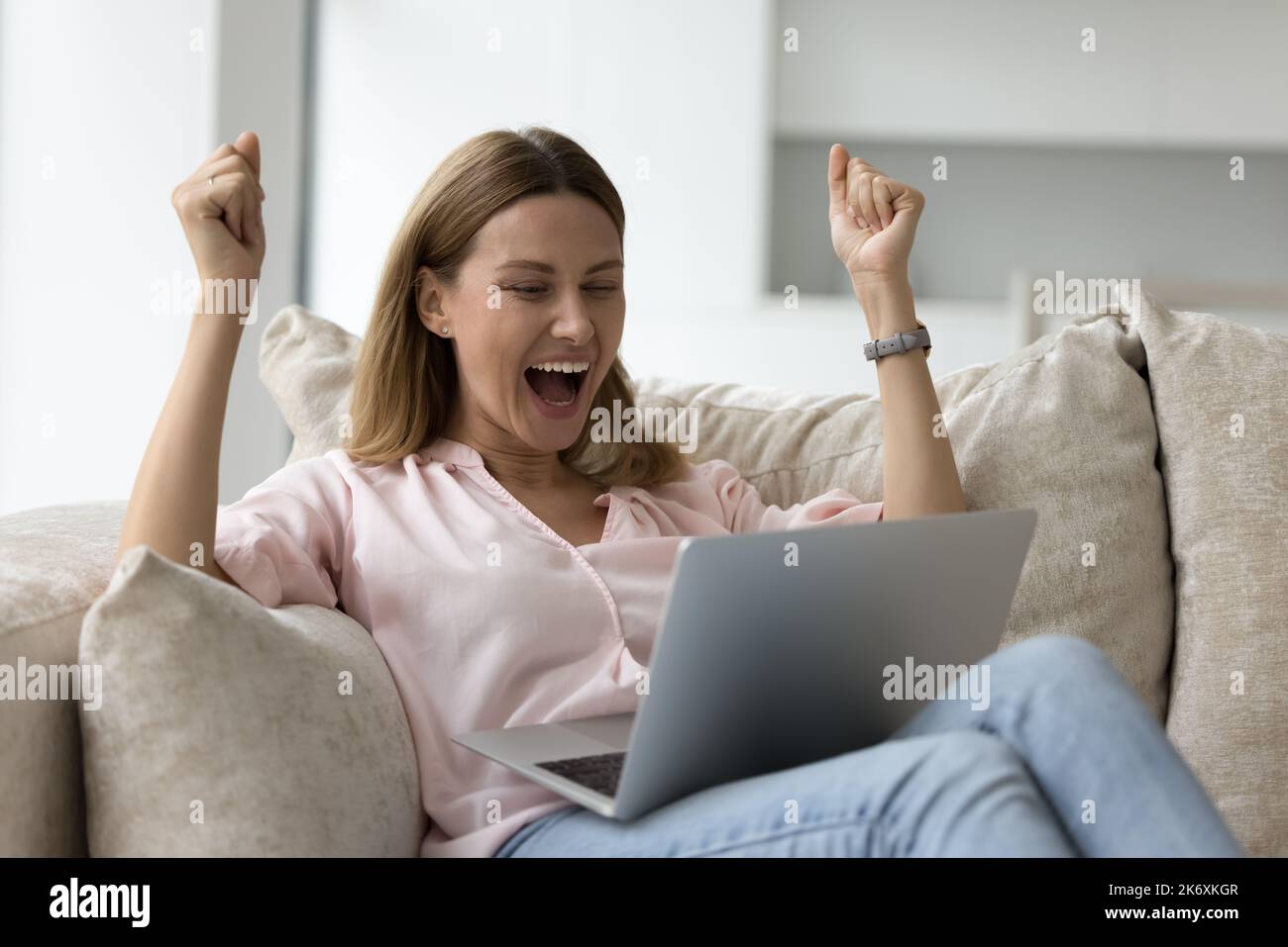 Frau liest Nachrichten auf dem Laptop, feiert Erfolg, freut sich Stockfoto