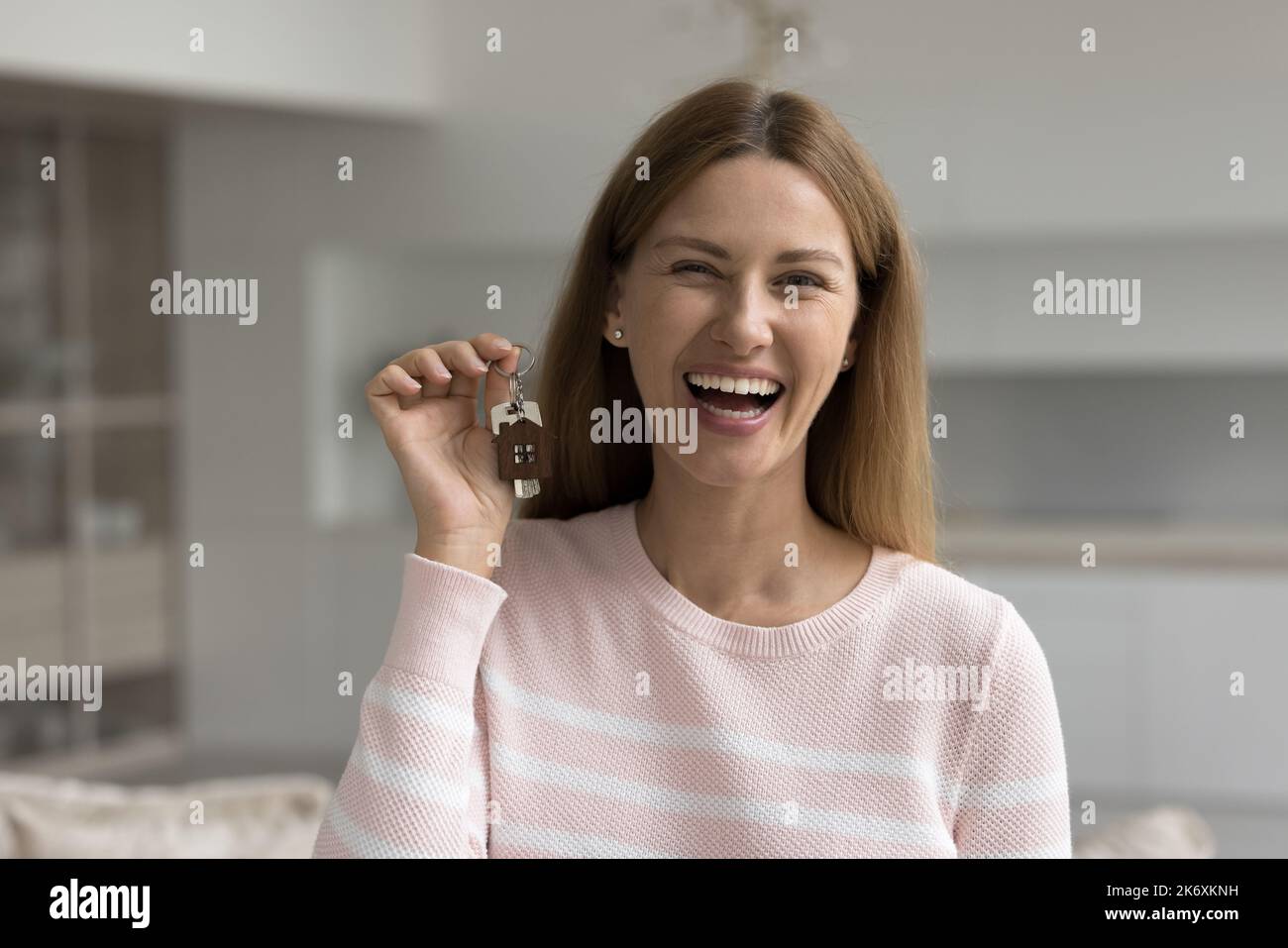 Fröhliche junge Frau posiert für die Kamera mit Schlüsseln in der Hand Stockfoto
