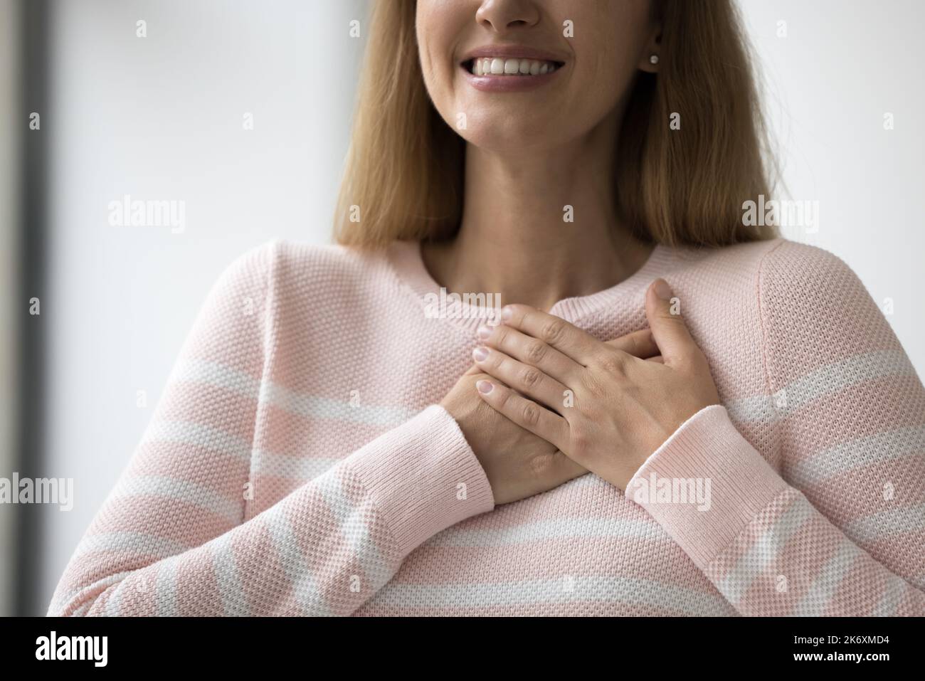 Aufrichtige Frau drückt Dankbarkeit mit gefalteten Händen auf der Brust aus, Nahaufnahme Stockfoto