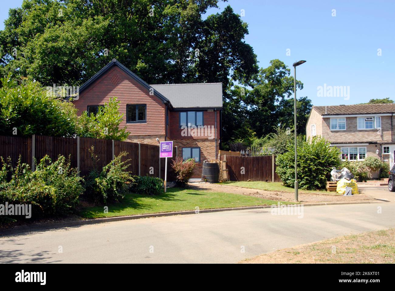 Vor kurzem fertiggestellte Haus, aber fahren noch nicht gemacht, zum Verkauf auf einer ruhigen Straße, mit Agent's Board draußen und mehrere Eichen hinter Stockfoto