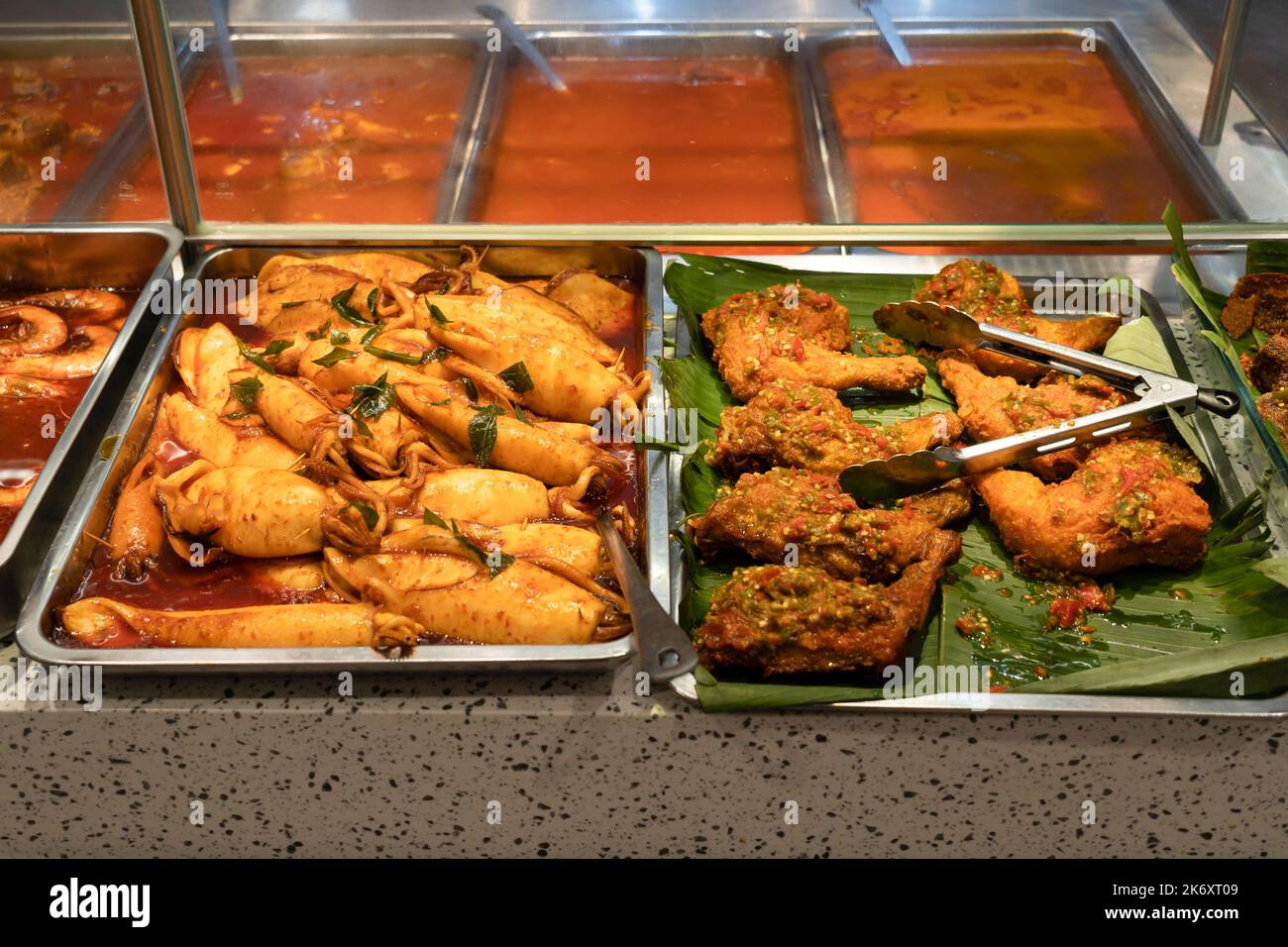 Nahaufnahme der Tintenfische und würzigen gebratenen Hähnchendrumsticks am Food Court Stand. Stockfoto