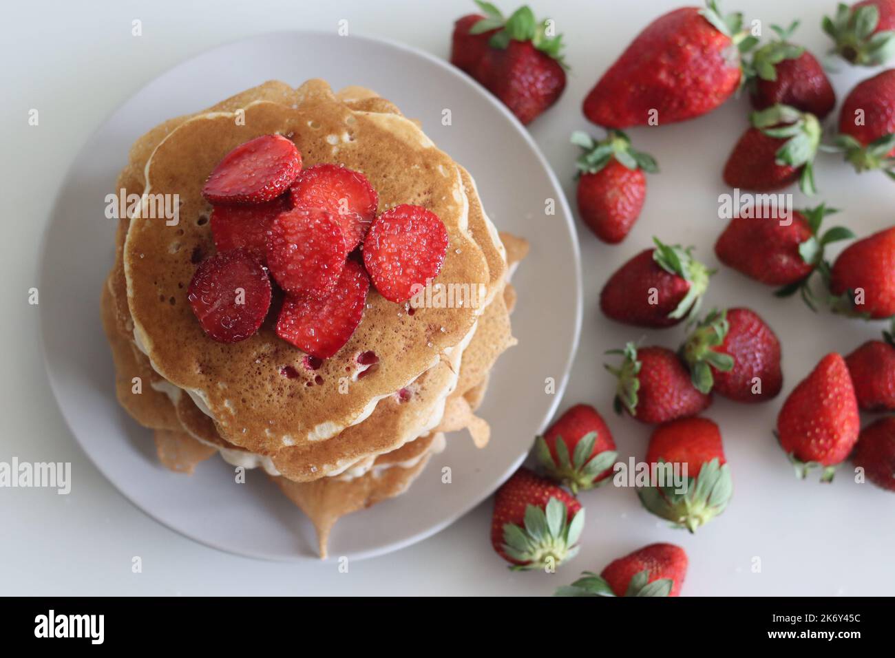 Erdbeerpfannkuchen. Weiche und flauschige Buttermilchpfannkuchen mit frischen Erdbeeren, die mit frisch geschnittenen Erdbeeren zubereitet werden, dem Teig aus Mehl hinzugefügt, b Stockfoto