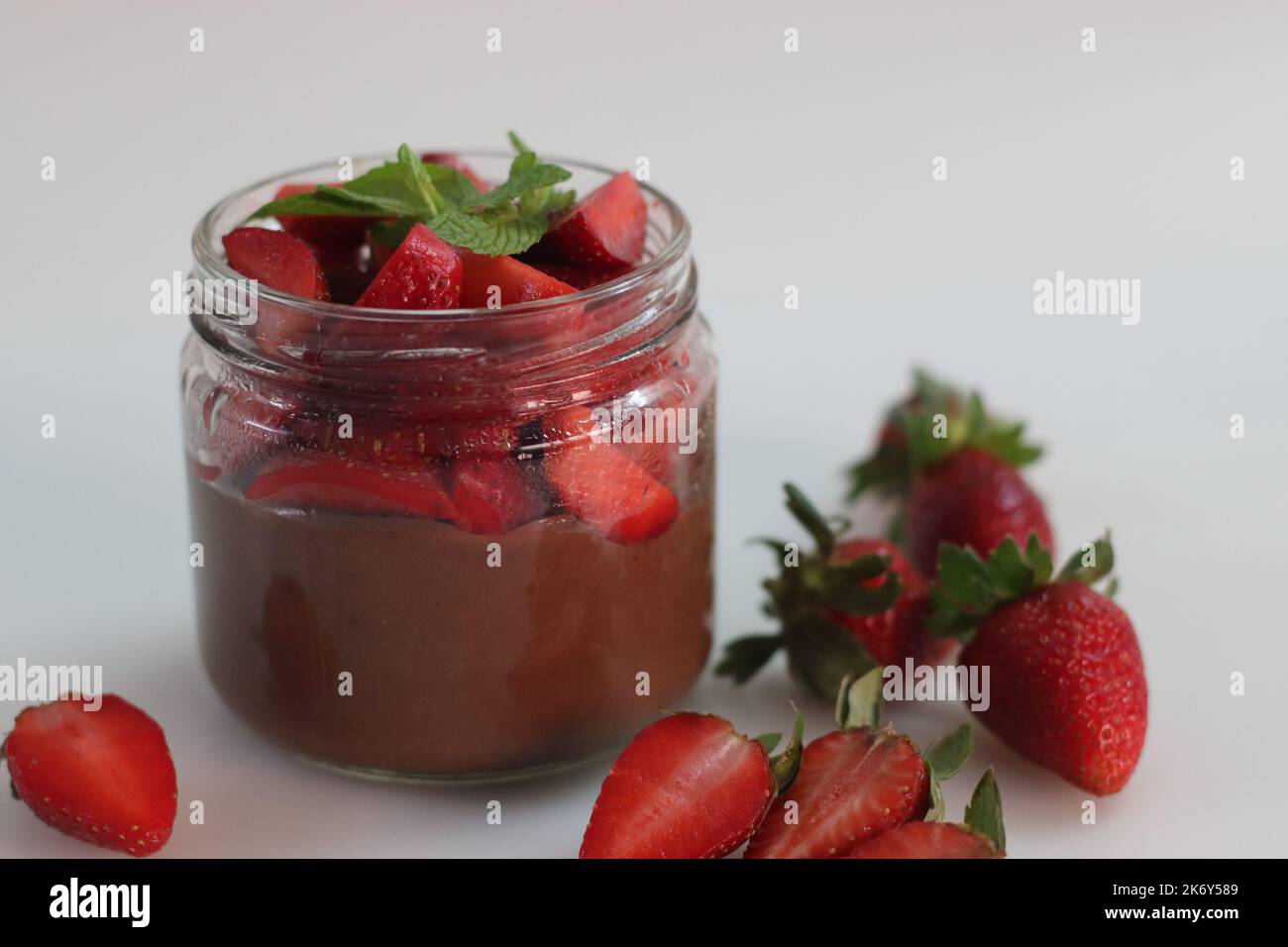 Schokoladenpudding mit Erdbeere. Schokoladenpudding serviert mit frisch gehackten Erdbeeren. Ein schnelles und einfaches Dessert, serviert in einer Glasflasche. Schuss auf WH Stockfoto