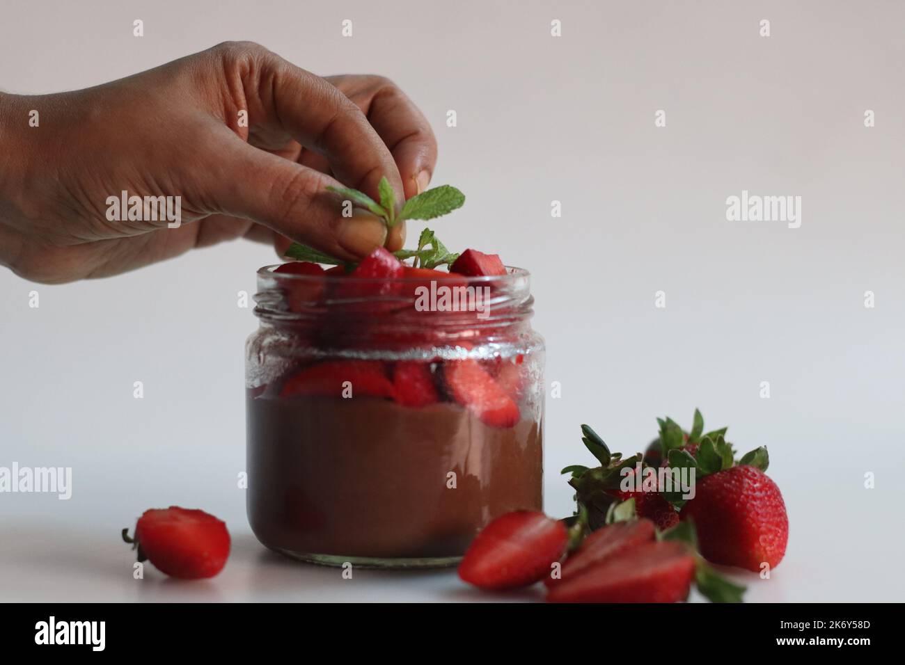 Schokoladenpudding mit Erdbeere. Schokoladenpudding serviert mit frisch gehackten Erdbeeren. Ein schnelles und einfaches Dessert, serviert in einer Glasflasche. Schuss auf WH Stockfoto