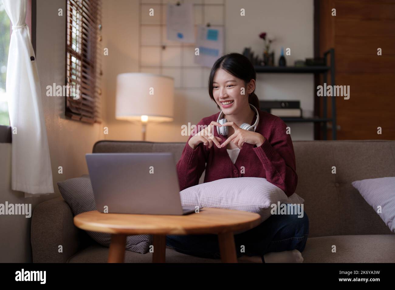 Attraktive lächelnde junge Frau Videoanruf von Laptop auf Sofa zu Hause. Lifestyle-Konzept Stockfoto