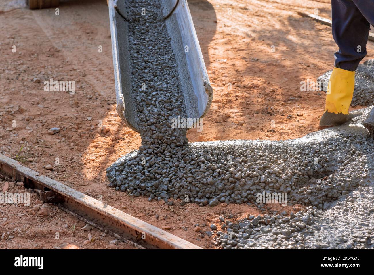 Betonbauunternehmen gießt feuchten Beton für die Pfeilung der Auffahrt, während es nass ist Stockfoto