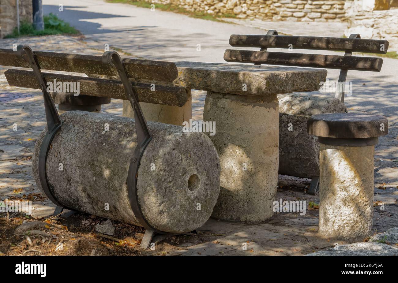 Schattige Sitzgelegenheiten und Tische aus alten Mühlsteinen auf einem spanischen Dorfplatz Stockfoto