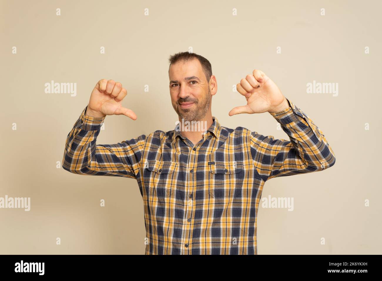 Studioportrait eines lustigen, stolzen Mannes mit 40s Daumen auf sich selbst, der sagt, er sei wirklich cool, sieht erfolgreich und selbstbewusst aus und trägt ein Hemd Stockfoto
