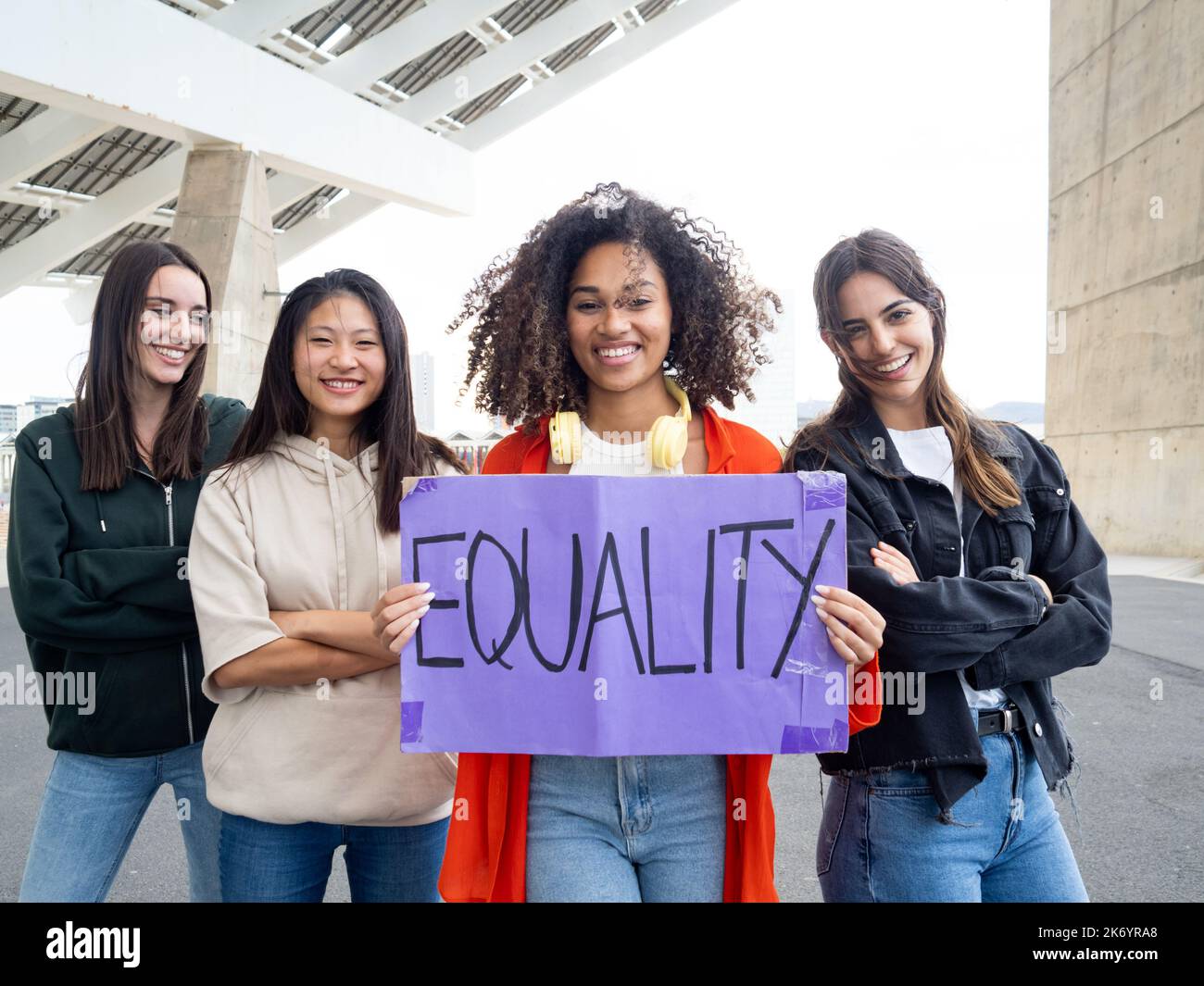 Gruppe von fröhlichen multiethnischen Mädchen, die mit einem Schild auf die Kamera blicken, auf dem steht: Gleichheit. Feminismus, ermächtigte Frau Stockfoto