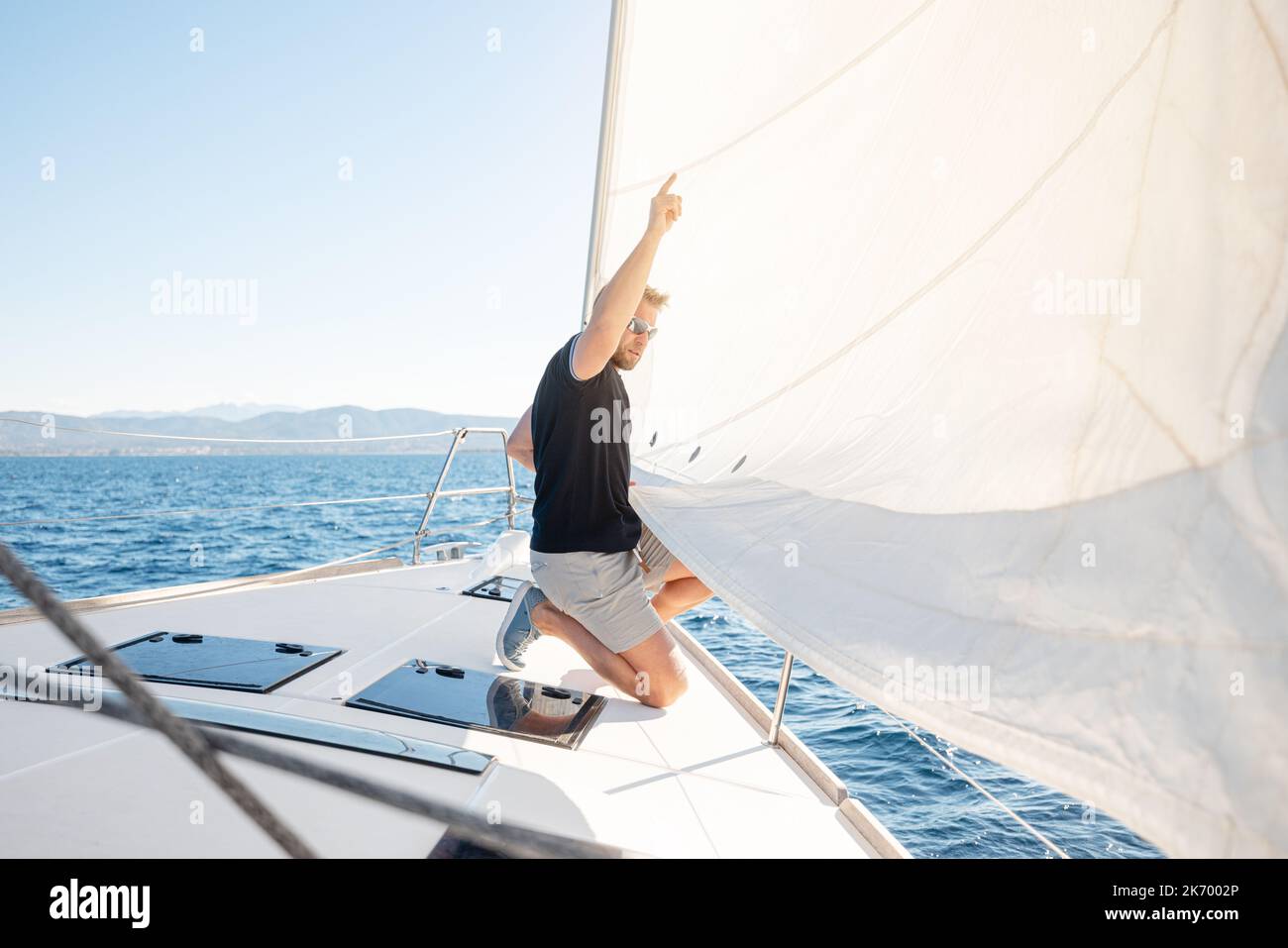 Mann, der auf seinem Boot Segel setzt Stockfoto