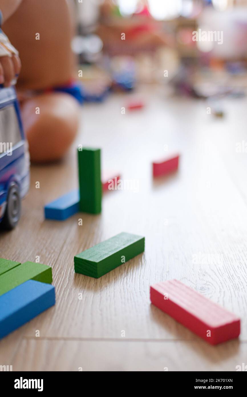 Einige bunte Spielzeughölzer und ein Van, der auf einem Hartholzboden auf einem Indoor-Spielplatz zusammenbricht Stockfoto