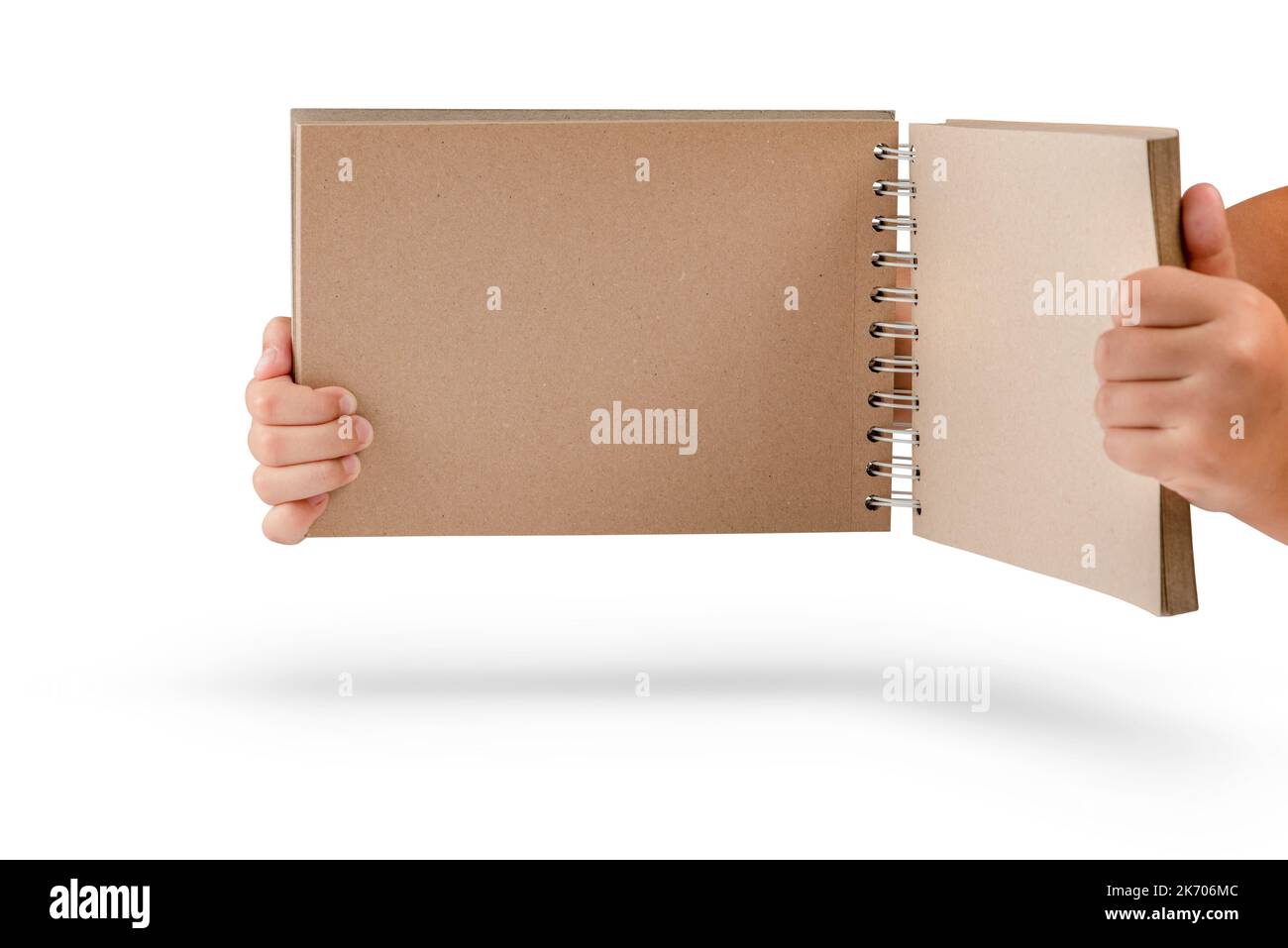 Notizblock auf weißem Hintergrund isoliert. Brauner Notizblock aus recyceltem Papier auf weißem Hintergrund in den Händen eines Kindes Stockfoto