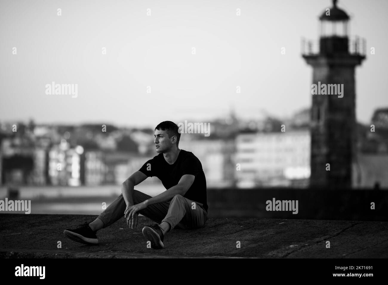 Ein hübscher junger Mann sitzt auf der Promenade. Schwarzweiß-Foto. Stockfoto