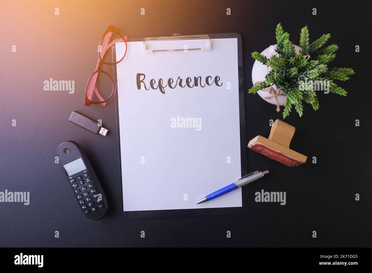 Notebook mit „Referenz“ auf dem Tisch, Arbeitsbereich im Büro mit Mobiltelefon, usb-Laufwerk, Brille und grüner Pflanze Stockfoto