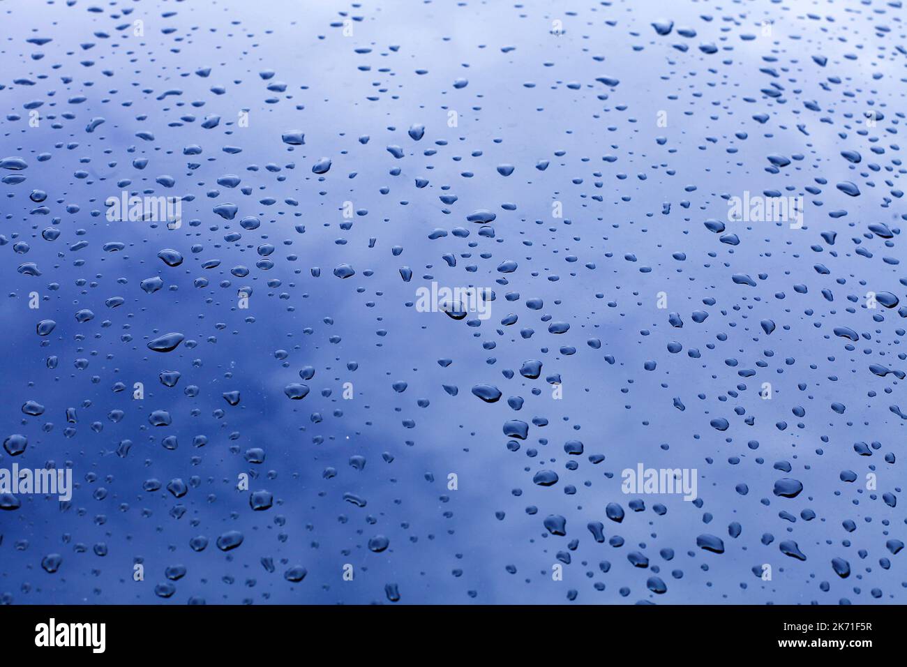 Wassertropfen auf Glas mit Spiegelung des blauen Himmels Stockfoto