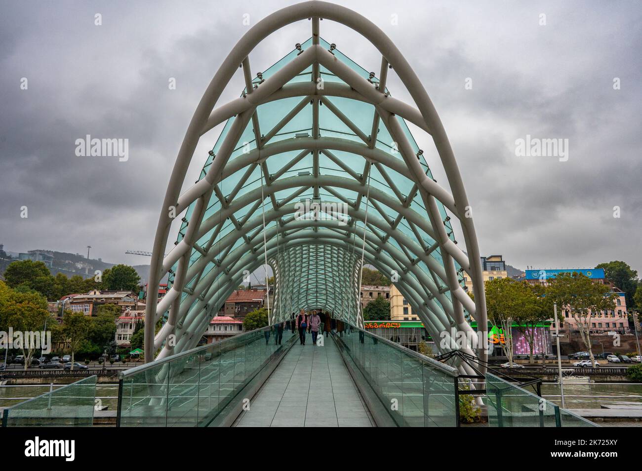 Die Friedensbrücke ist eine bogenförmige Fußgängerbrücke, eine Stahl- und Glaskonstruktion, die den Fluss Kura in Tiflis überquert Stockfoto