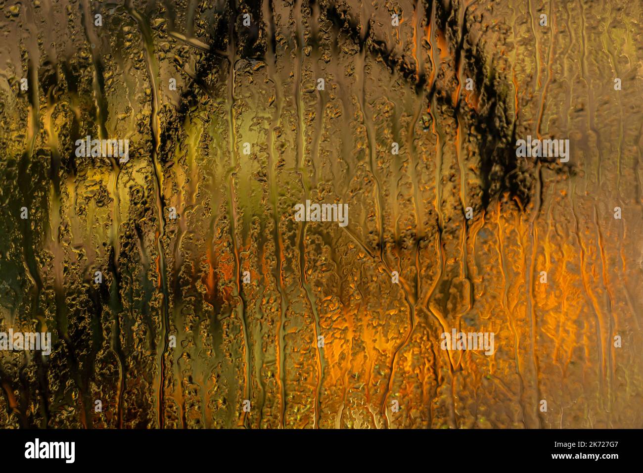 Vernebelte Fensterscheibe mit Blick auf den Herbstgarten und gelbem Hintergrund Stockfoto