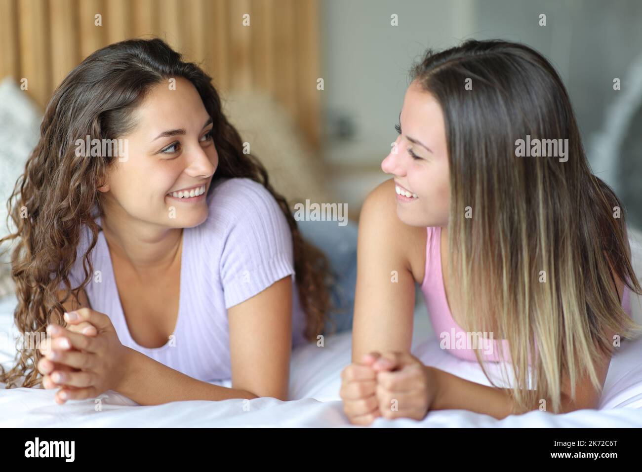 Zwei glückliche Freunde, die sich im Schlafzimmer auf dem Bett unterhielten Stockfoto