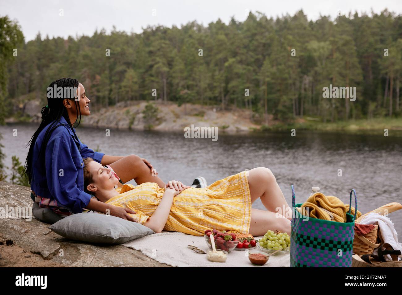 Weibliches Paar mit Picknick am Fluss Stockfoto