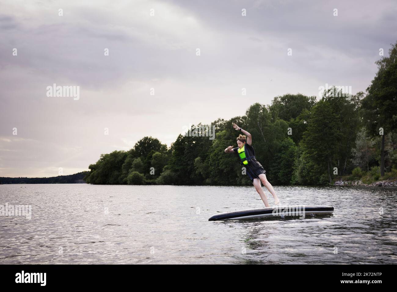 Junge springt vom Paddle Board auf dem See Stockfoto